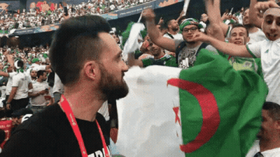 Man In Black Shirt Holding Flag Before Crowd GIF