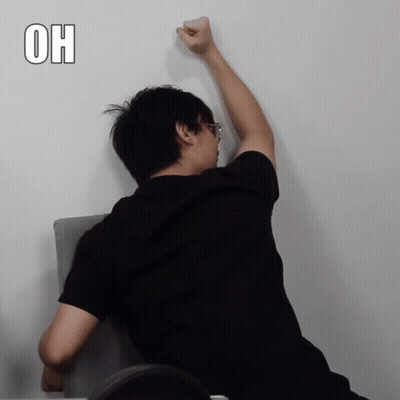 Man In Black Shirt Leaning Against Wall With Fist In Air Saying Oh GIF