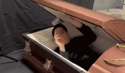 Man In Black Shirt Lying In Open Coffin GIF