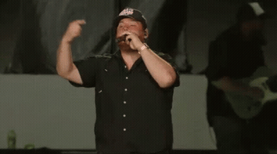 Man In Black Shirt Singing Into Microphone With Eagles Hat GIF