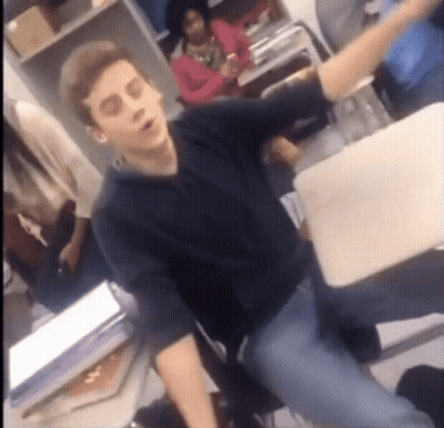 Man In Black Shirt Sitting At Desk With Arm Outstretched GIF