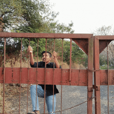 Man In Black Shirt Sitting Behind Red Gate GIF