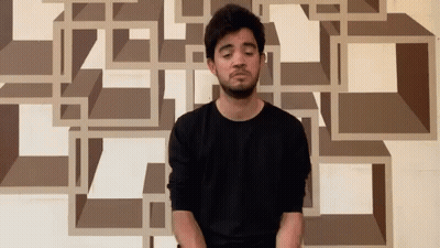 Man In Black Shirt Sitting In Front Of Geometric Wall GIF