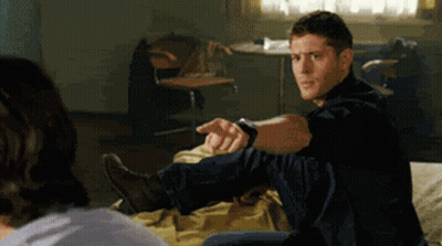 Man in Black Shirt Sitting on Bed Pointing