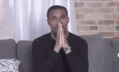 Man In Black Shirt Sitting On Couch With Hands Folded In Prayer GIF
