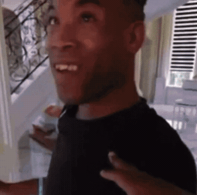 Man In Black Shirt Smiling In Front Of Stairs GIF