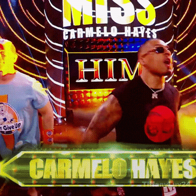 Man In Black Shirt Standing Before Carmelo Hayes Sign GIF