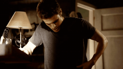 Man In Black Shirt Standing Before Lamp In Dark Room GIF