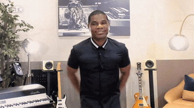 Man In Black Shirt Standing In Front Of Keyboard And Guitars GIF