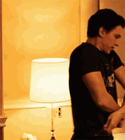 Man In Black Shirt Standing In Front Of Lamp GIF