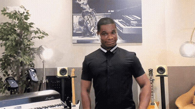 Man In Black Shirt Standing In Front Of Piano Saying A GIF