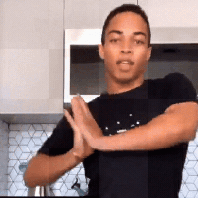 Man In Black Shirt Standing In Kitchen With Hands Folded In Prayer GIF