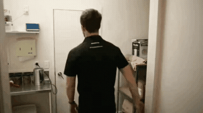 Man In Black Shirt Standing In Room With Shelf GIF