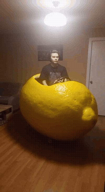 Man In Black Shirt Standing Next To Giant Lemon GIF
