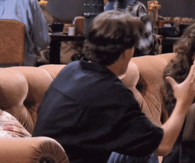 Man In Black Shirt Talking To Woman On Couch GIF