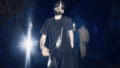 Man In Black Shirt Walking Dark With Bag GIF