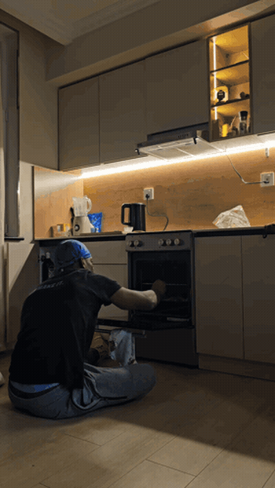 Man In Black Shirt With A Kneeling At Oven GIF