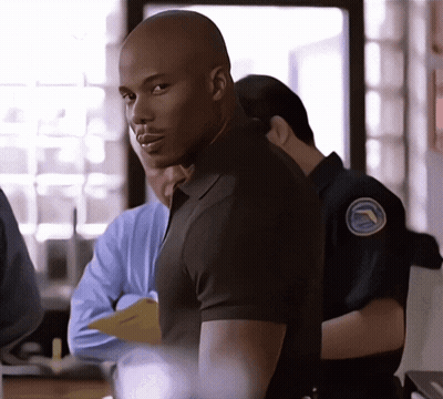 Man In Black Shirt With Blue Badge GIF