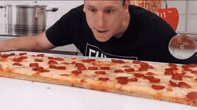 Man In Black Shirt With T Looking At Long Pepperoni Pizza GIF
