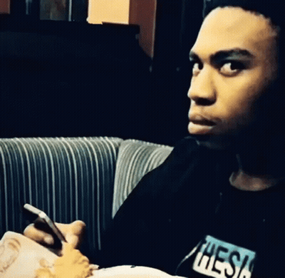 Man In Black Shirt With Thesis Looking At Phone GIF