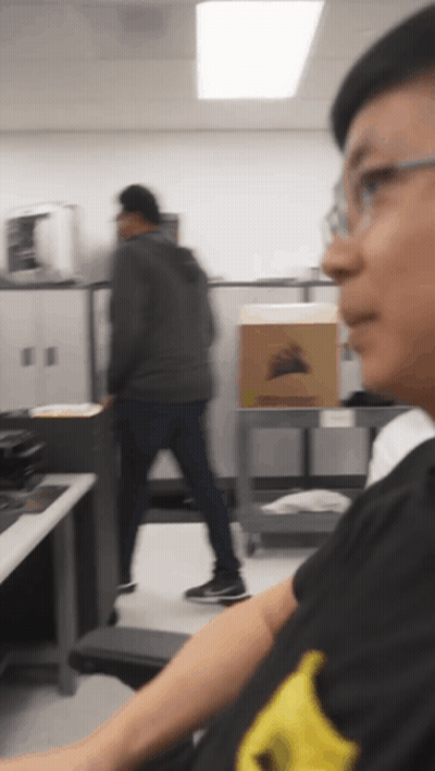Man In Black Shirt With Yellow Stripe Looking At Box GIF