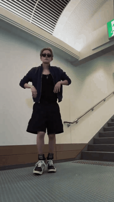 Man in Black Shorts and Jacket in Front of Staircase