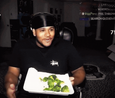 Man In Black Stussy Shirt Holding Broccoli Tray GIF