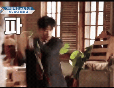 Man In Black Suit Dancing In Room With Plant GIF