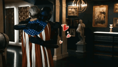 Man In Black Suit Hugging Woman In American Flag Costume GIF
