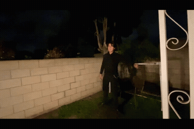 Man In Black Suit In Front Of Brick Wall GIF