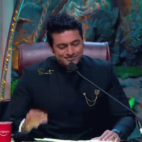 Man In Black Suit Sitting At Microphone With Colgate Can GIF