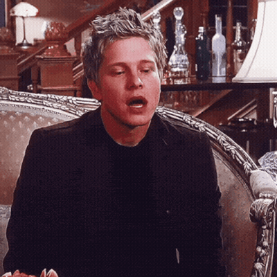 Man In Black Suit Sitting On Chair With Mouth Open GIF