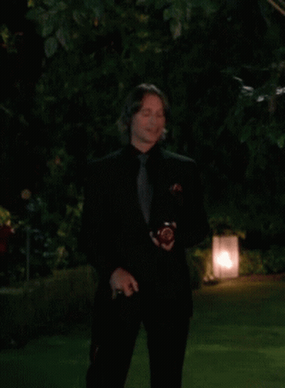 Man In Black Suit Standing In Dark Garden GIF