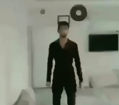 Man In Black Suit Standing In Living Room With Wreath GIF