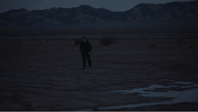 Man In Black Suit Walking In Desert GIF