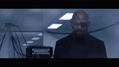 Man In Black Suit With Eye Patch In Hallway GIF