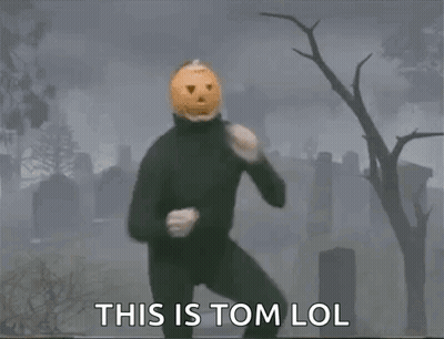 Man In Black Suit With Pumpkin Head In Cemetery GIF