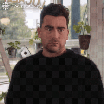 Man In Black Sweater In Front Of Schitts Creek Sign GIF
