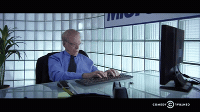 Man In Black Sweater Next To Woman In Chair GIF