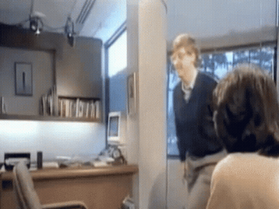 Man In Black Sweater Next To Woman In Office GIF
