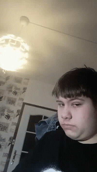 Man In Black Sweater With Letter T Looking At Camera GIF