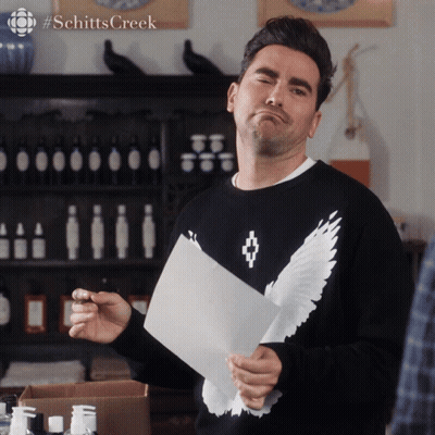 Man In Black Sweater With White Wings Holding Paper GIF