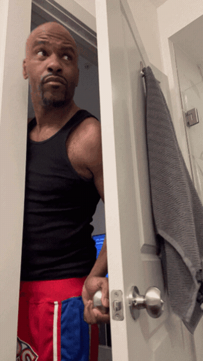 Man In Black Tank Top And Red Shorts In Bathroom GIF