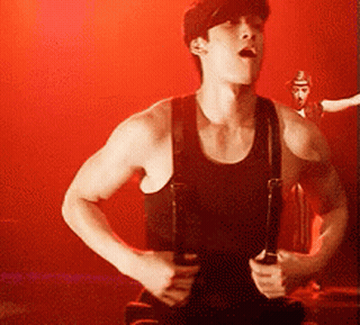 Man in Black Tank Top and Suspenders Holding Guitar