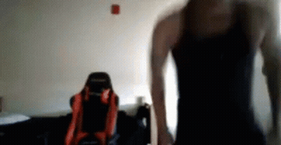 Man In Black Tank Top In Front Of Red And Black Chair GIF