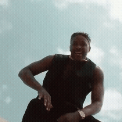 Man In Black Tank Top Sitting On Rock GIF