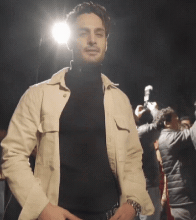 Man In Black Turtleneck And White Jacket In Crowd GIF