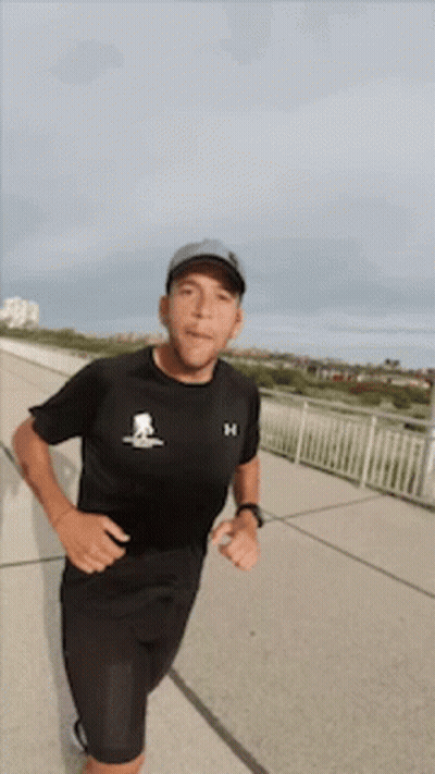 Man In Black Under Armour Shirt Running On Sidewalk GIF