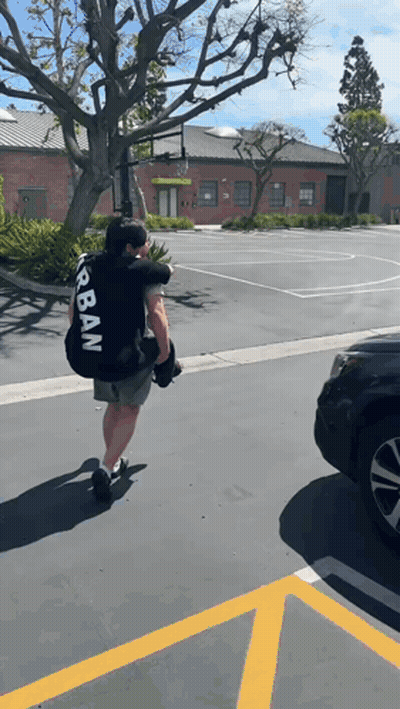 Man In Black Urban Shirt Carrying Large Bag GIF