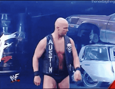 Man In Black Vest Saying Austin In Front Of Pile Of Cars GIF